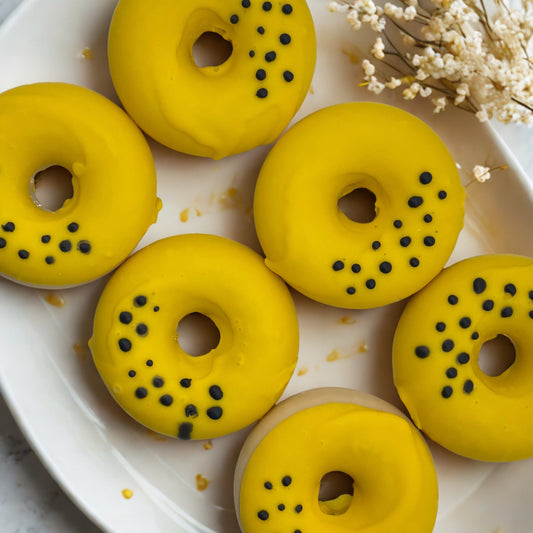 Yellow donut-shaped pastries with black specks on a white plate with dried flowers.